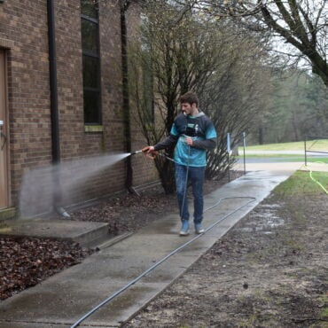 Prime & Shine technician pressure washing a brick commercial building exterior in Northern Indiana