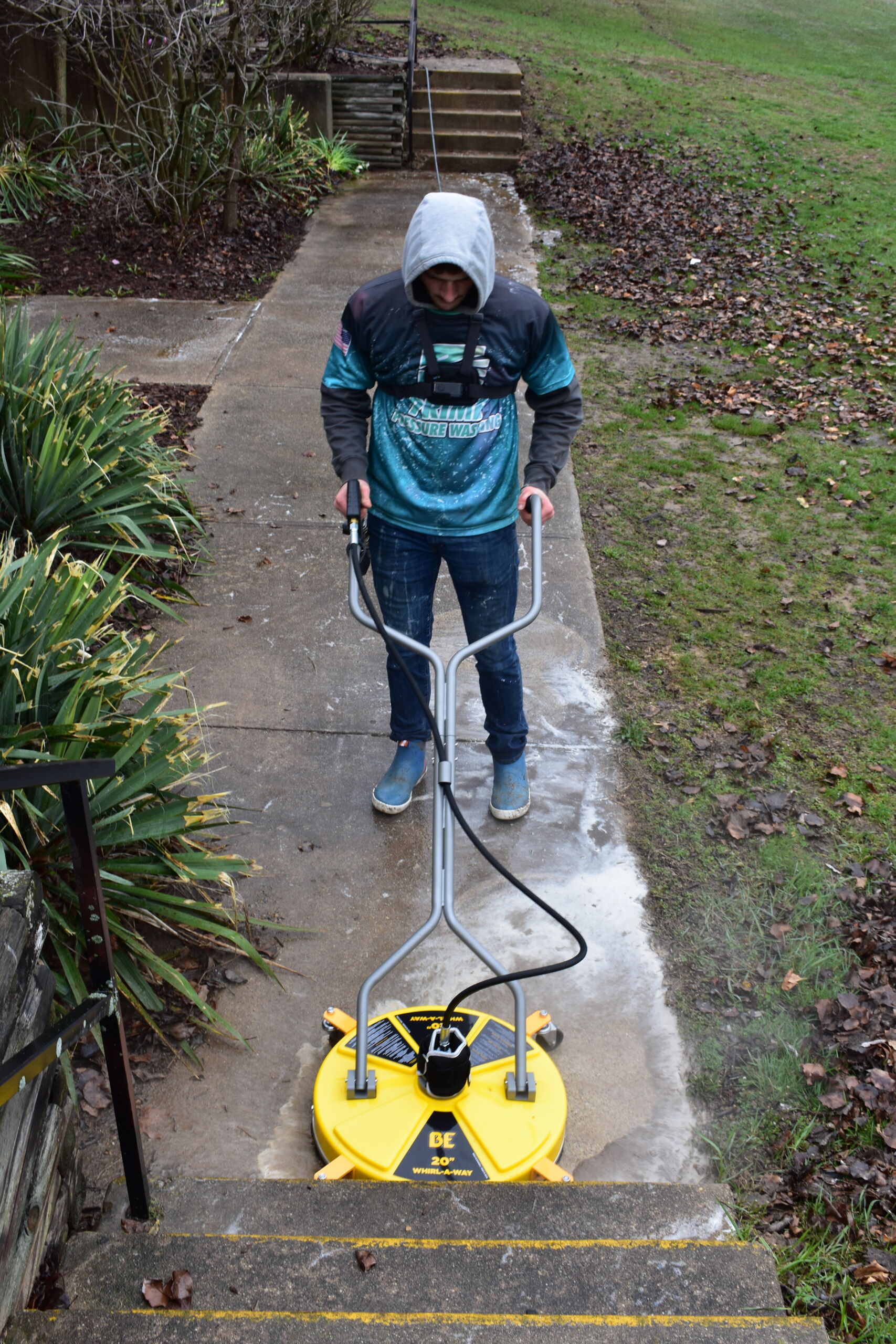 Prime & Shine technician using a BE 20-inch Whirl-A-Way surface cleaner to scrub a concrete sidewalk outside a commercial building