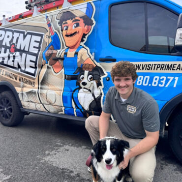 Micheal Norris kneeling with dog beside branded company van