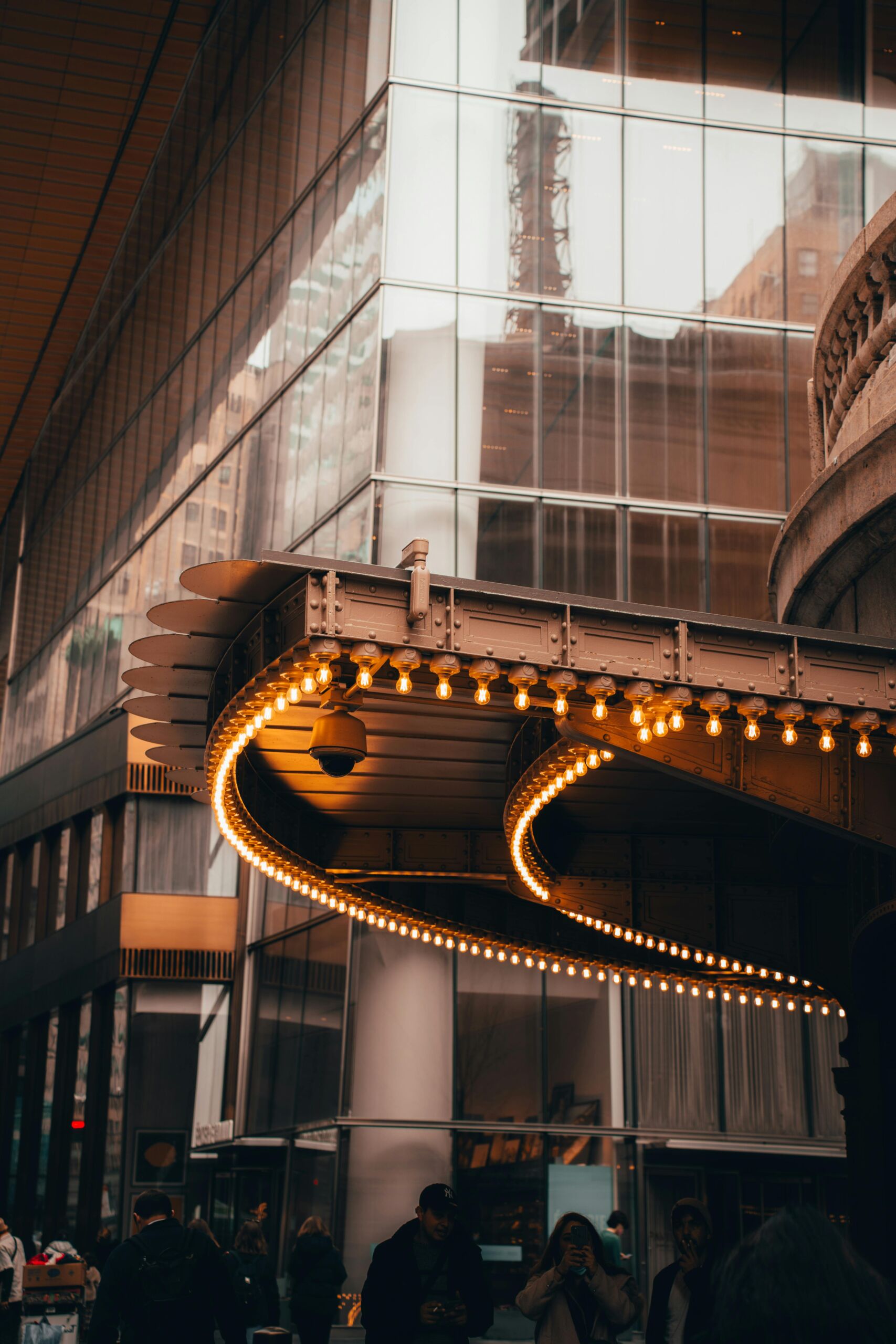 Commercial building entrance with decorative warm Edison bulb lighting along a curved metal canopy