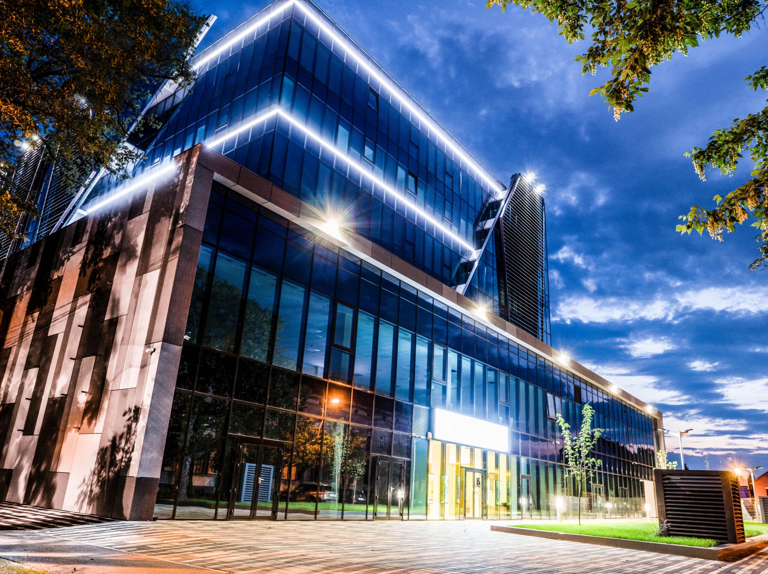 Modern glass office building with professional LED exterior lighting illuminated at night